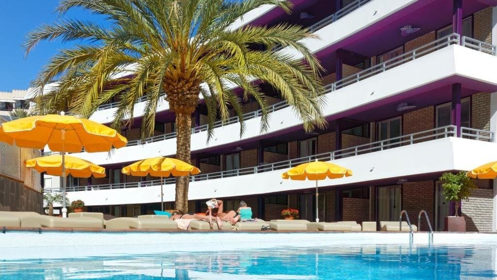 Budynek apartamentowy z palmą, parasolami i basenem